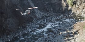Hubschrauber fliegt über felsigem Fluss — Stockfoto