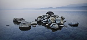 Pilha de pedras subindo acima da água — Fotografia de Stock