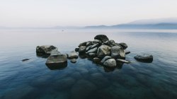 Pile of stones rising above water — Stock Photo