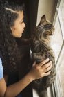 Девушка с кошкой у окна — стоковое фото
