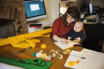 Donna seduta con bambino in grembo scrivere nel taccuino — Foto stock