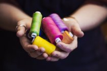 Woman holding hands out full of bobbins — Stock Photo