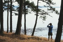 Uomo in piedi sulla spiaggia e guardando attraverso binocoli — Foto stock