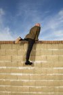 Homem escalando sobre parede de tijolo amarelo — Fotografia de Stock