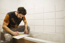 Будівельник, плитка, що працює у ванній — стокове фото