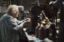 Donna anziana nel laboratorio di un calzolaio . — Foto stock