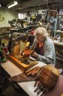 Older woman in a shoemaker's workshop. — Stock Photo