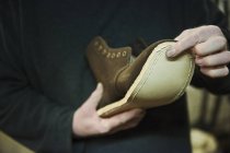 Worker attaching sole to leather boot. — Stock Photo