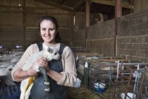 Smiling woman holding newborn lamb — Stock Photo