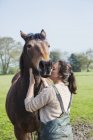 Mulher beijando um cavalo marrom — Fotografia de Stock