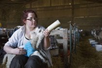 Woman feeding newborn lamb — Stock Photo