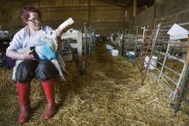 Woman feeding newborn lamb — Stock Photo