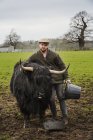 Farmer with black highland cow — Stock Photo