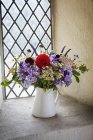 Bouquet de fleurs dans une cruche blanche — Photo de stock