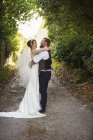 Recién casados de pie al aire libre - foto de stock
