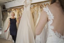 Жінка намагається на весільних сукнях — стокове фото