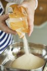 Persona versando zucchero dal sacchetto di plastica — Foto stock