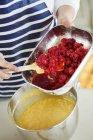 Person adding raspberries to cake batter — Stock Photo