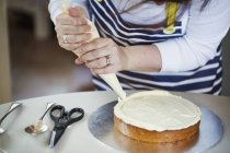 Person decorating cake with cream — Stock Photo