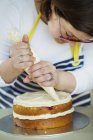 Frau dekoriert Kuchen mit Sahne. — Stockfoto