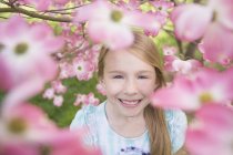 Giovane ragazza guardando attraverso fiore — Foto stock