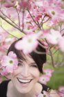Mujer mirando a través de ramas florecientes - foto de stock