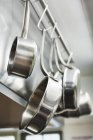 Кастрюли и сковородки, висящие на металлических крюках — стоковое фото