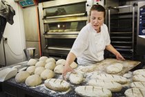 Mujer colocando panes recién horneados - foto de stock