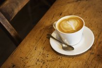 Tasse Cappuccino auf rustikalem Holztisch — Stockfoto