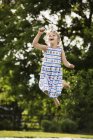 Chica en sundress saltar en trampolín - foto de stock
