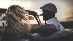 Hombre y mujer montando en coche descapotable clásico - foto de stock