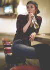 Frau sitzt auf Schemel und trinkt — Stockfoto