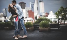 Пара обнимается на городской крыше — стоковое фото