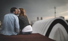 Coppia seduta e baciare sul tetto della città . — Foto stock