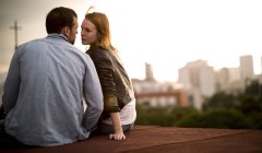 Couple sitting and kissing on city rooftop. — Stock Photo