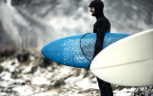 Surfista llevando tabla de surf - foto de stock