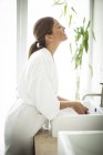 Жінка стоїть біля раковини у ванній — стокове фото