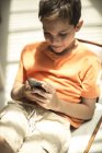 Мальчик, сидящий, глядя на мобильный телефон — стоковое фото