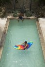 Ragazzo seduto sulla zattera della piscina — Foto stock