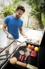 Uomo girando il cibo sul barbecue . — Foto stock