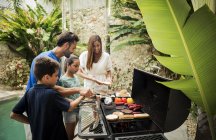 Famiglia in piedi al barbecue — Foto stock