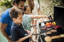 Famille debout au barbecue — Photo de stock