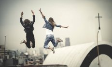 Women jumping on rooftop — Stock Photo