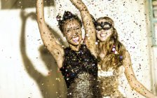 Mujeres jóvenes bailando con confeti cayendo . - foto de stock
