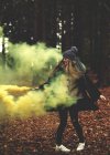 Mujer agitando bengalas de humo amarillo en el bosque
. - foto de stock