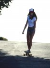 Jeune femme à cheval skateboard — Photo de stock