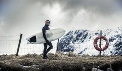 Surfeur portant une planche de surf — Photo de stock