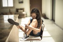 Дівчина сидить дивлячись на мобільний телефон — стокове фото