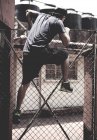 Homme grimpant par-dessus la clôture — Photo de stock