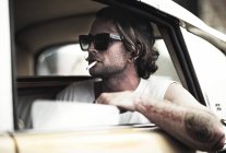 Uomo con i baffi seduto in macchina — Foto stock